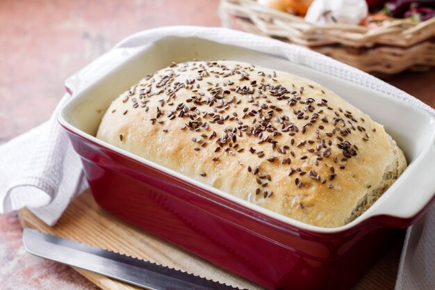 Pane casereccio con semi di lino in teglia in ceramica rossa