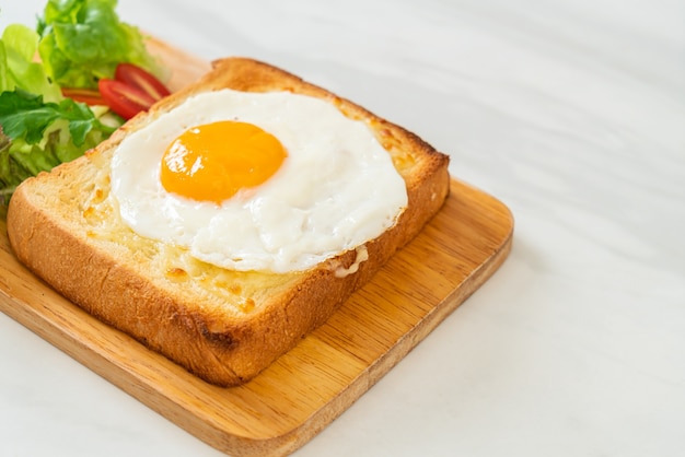 pane casereccio tostato con formaggio e uovo fritto sopra con insalata di verdure per colazione