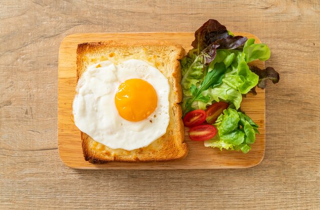 pane casereccio tostato con formaggio e uovo fritto sopra con insalata di verdure per colazione