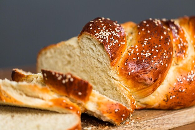 Pane challah fresco affettato sul tavolo di legno.