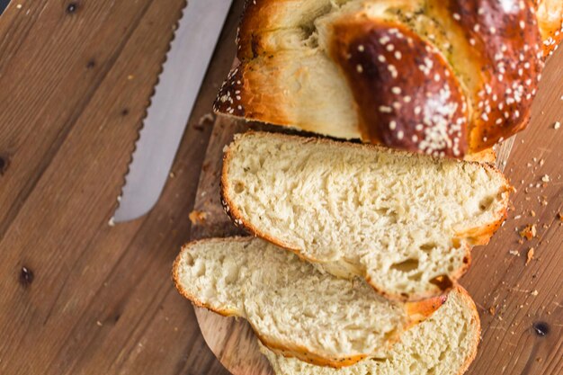 Pane challah fresco affettato sul tavolo di legno.