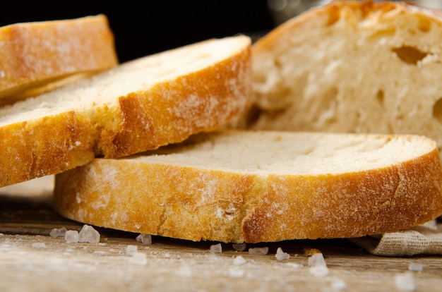 Pane ciabatta. Fette di ciabatta con aglio, sale sul tavolo di legno sul panno di lino.