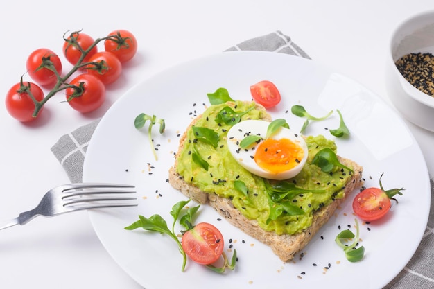 Pane con avocado verdure frutta e uova su sfondo bianco Concetto di colazione sana