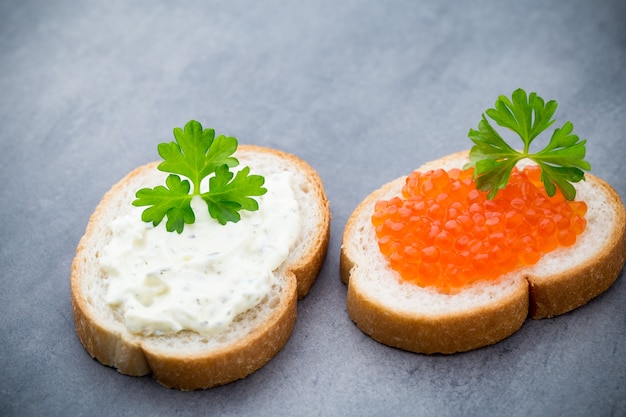 Pane con crema di formaggio fresca e caviale rosso sul tavolo.