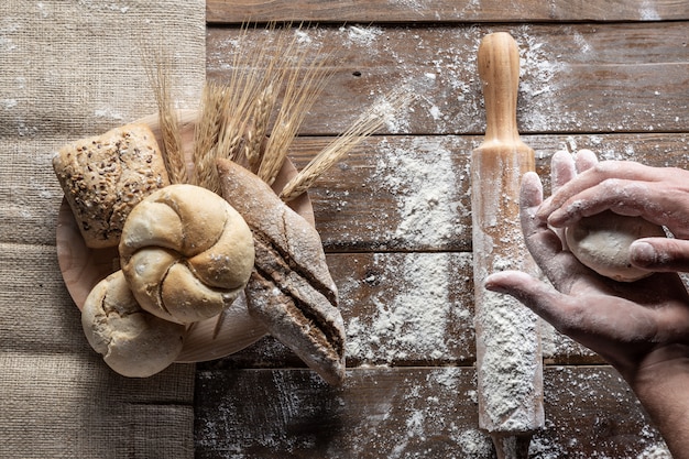 Pane con le orecchie e la farina del grano sul bordo di legno, vista superiore