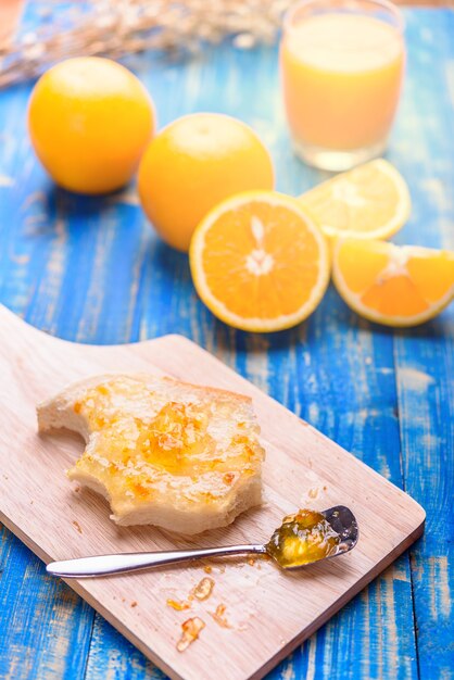 Pane con marmellata di arancia e arancia rossa sul tavolo di legno