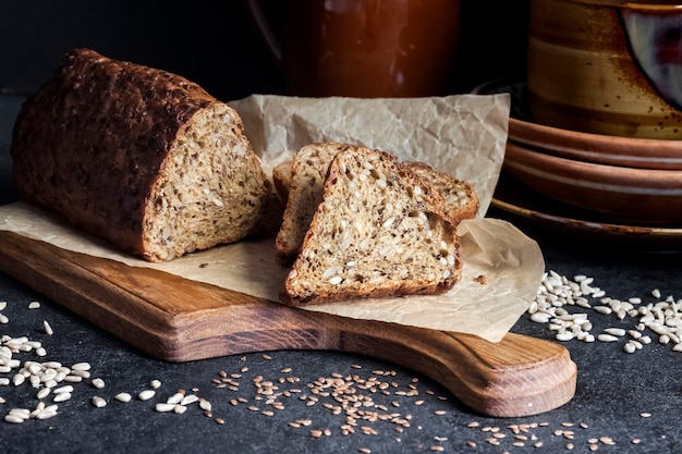 Pane con semi di girasole e lino su un tagliere di legno. Stoviglie in ceramica in background.