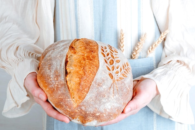 Pane cotto di pasta madre nelle mani delle donne. Creazioni fatte in casa e naturali