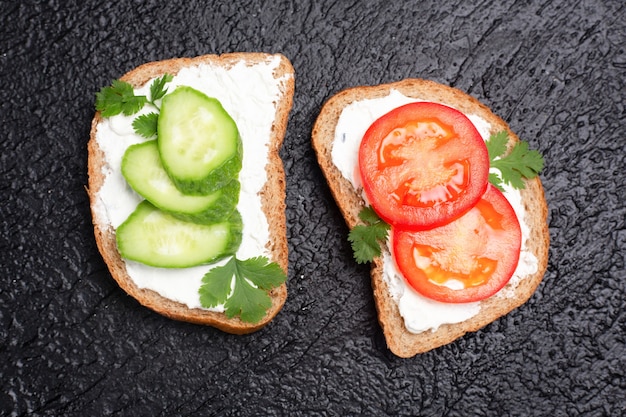 Pane croccante del panino della prima colazione sana con e pomodori su una tavola di legno