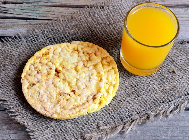 Pane croccante di grano intero con un bicchiere di succo sul vecchio tavolo di legno. Colazione sana o concetto di dieta.