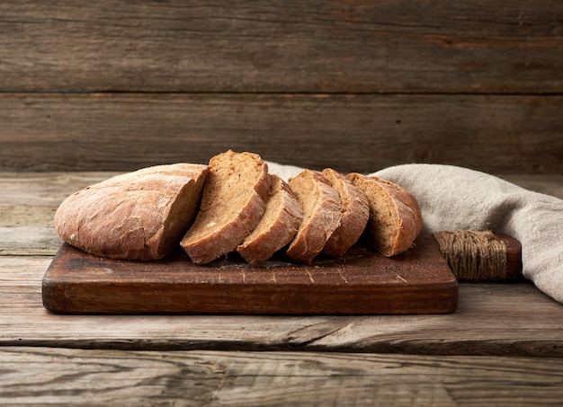 Pane di farina di segale al forno rotondo affettato su un tagliere di legno