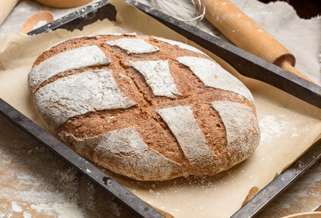 Pane di farina di segale ovale cotto in un foglio di cottura metallico sulla tavola