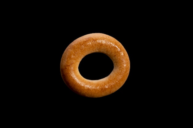 Pane di pasta choux di grano a forma di anello. bagel isolato su sfondo nero. Foto di alta qualità