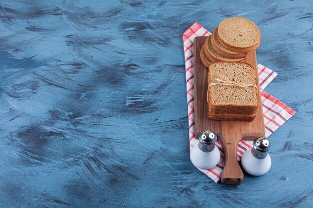 Pane di segale a fette su una tavola su un asciugamano, sul blu.