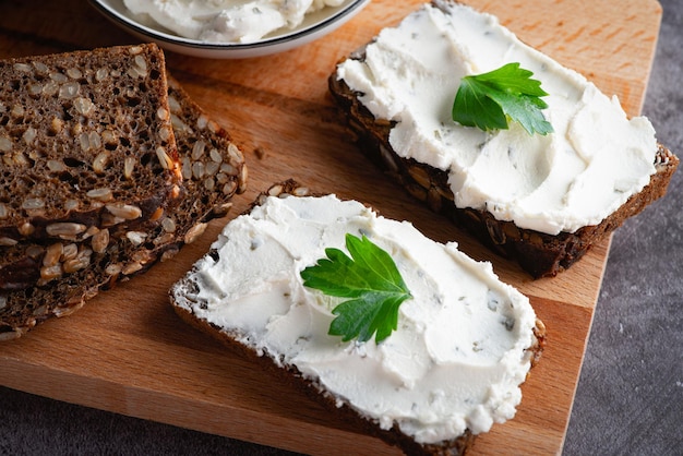 Pane di segale con crema di formaggio su tavola grigia Pane di segale integrale con semi