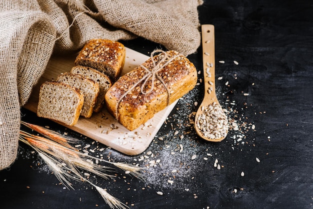 Pane di segale dolce con ingredienti diversi su fondo di legno nero