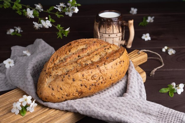 Pane di segale fresco fatto in casa con una tazza di latte in argilla sul tagliere di legno Colazione sana