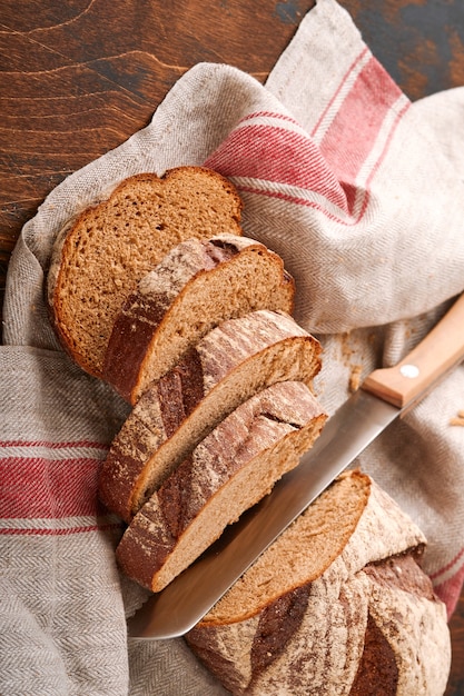 Pane di segale fresco fatto in casa. Pane tradizionale a lievitazione naturale di farro tagliato a fette su un fondo di legno rustico. Concetto di tradizionali metodi di cottura del pane lievitato. Messa a fuoco selettiva.