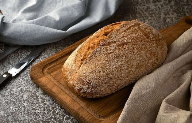 Pane di segale integrale su un tagliere con coltello sulla superficie grigia