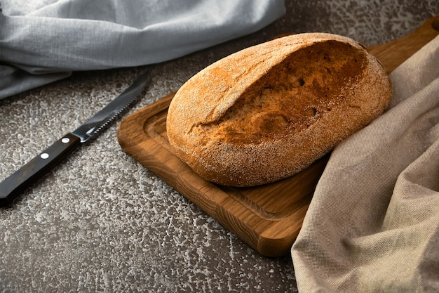 Pane di segale integrale su un tagliere con coltello sulla superficie grigia