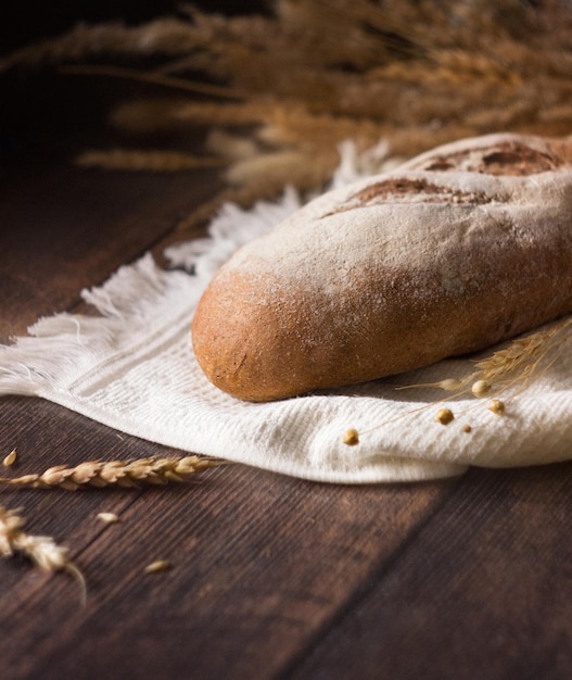 Pane di segale su tovagliolo e legno tra spighe di segale.