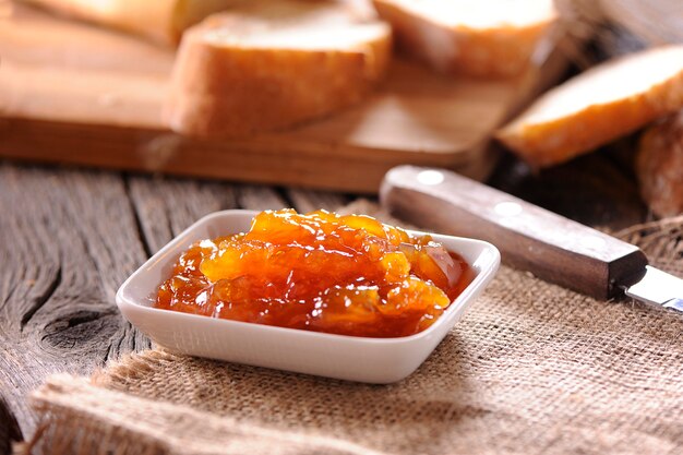 Pane e marmellata fatta in casa di arance sul tavolo di legno