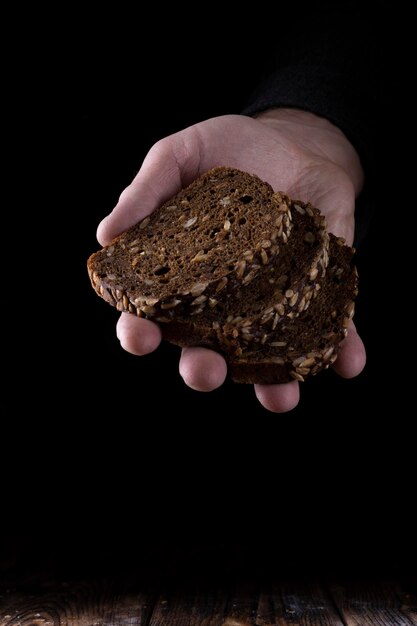 Pane fatto in casa a fette in mano su sfondo nero.