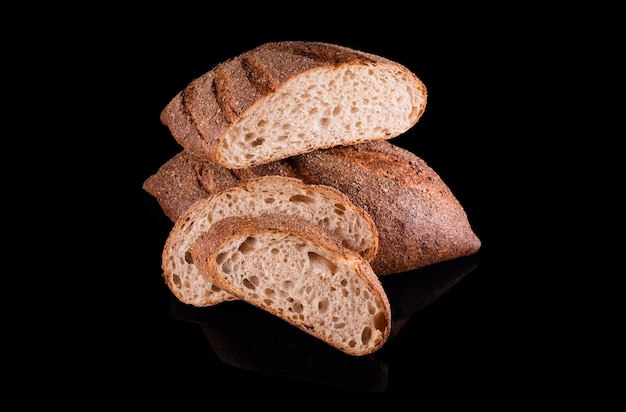 Pane fatto in casa appena sfornato isolato sul nero. Tagliare a metà il pane di segale con le fette. Mangiare sano e panetteria tradizionale, concetto di pane da forno.