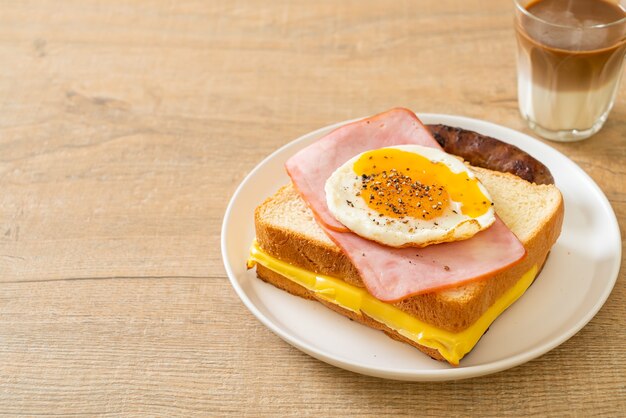 pane fatto in casa formaggio tostato condito con prosciutto e uovo fritto con salsiccia di maiale e caffè per colazione