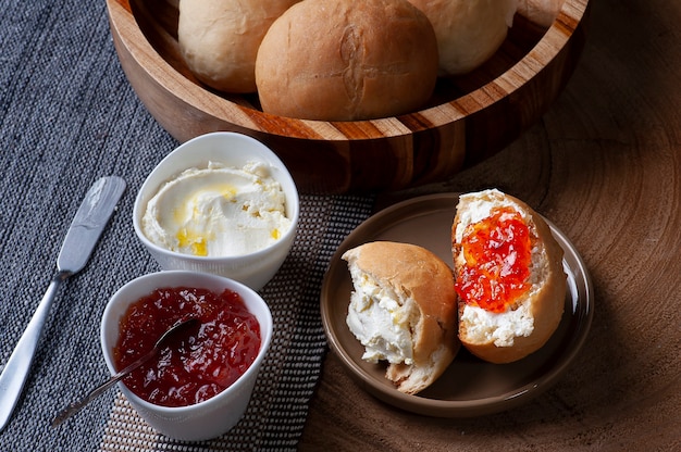 Pane fatto in casa in una ciotola di legno accompagnato da ricotta e marmellata