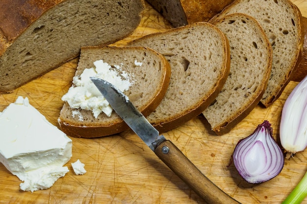 Pane fatto in casa su un tagliere di legno con ricotta Decorato con cipolle verdi fresche o cipollotti