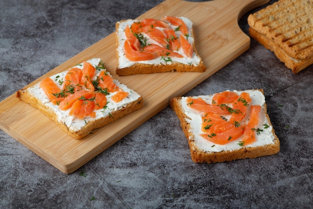 Pane fatto in casa su un tagliere di legno con salmone ed erbe aromatiche