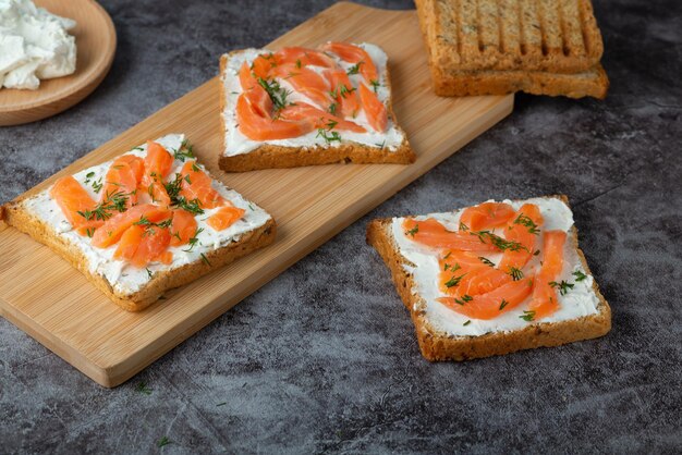 Pane fatto in casa su un tagliere di legno con salmone ed erbe aromatiche