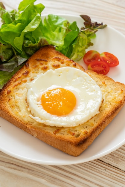 pane fatto in casa tostato con formaggio e uovo fritto sopra con insalata di verdure per colazione