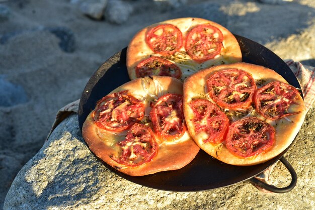 Pane focaccia italiano al forno coperto di fette di pomodoro