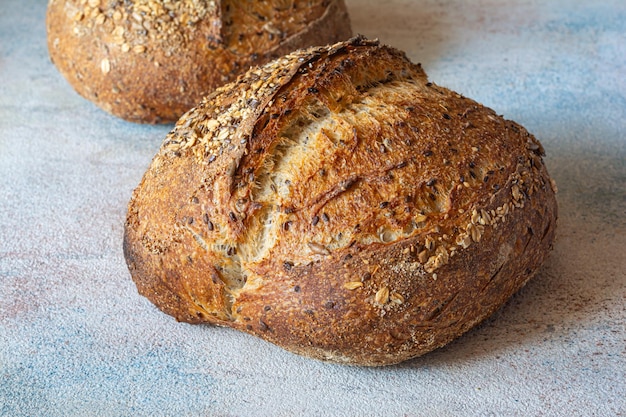 Pane fresco a pasta di grano intero con semi di lino, farina d'avena, semi di sesamo su sfondo colorato