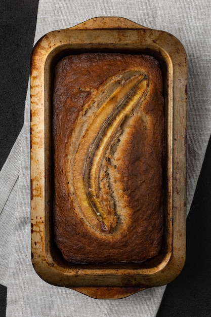 Pane fresco alla banana di forma rettangolare su tovagliolo in tessuto e sfondo nero