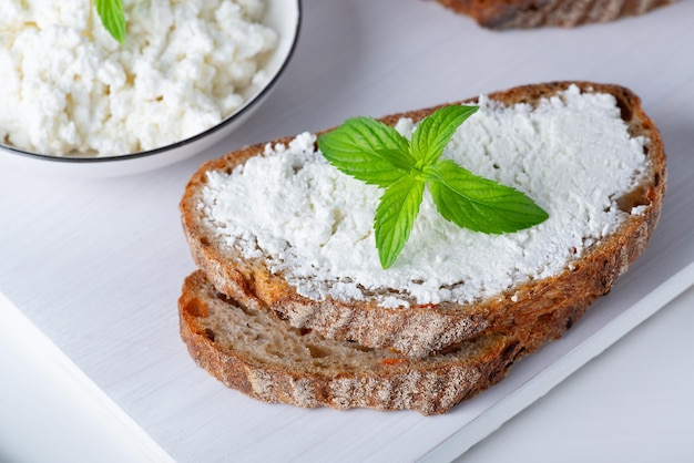 Pane fresco con le carote su un tagliere di legno bianco con la ricotta