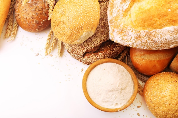 Pane fresco con semi di girasole sesamo grano e ciotola di legno di farina isolata su bianco