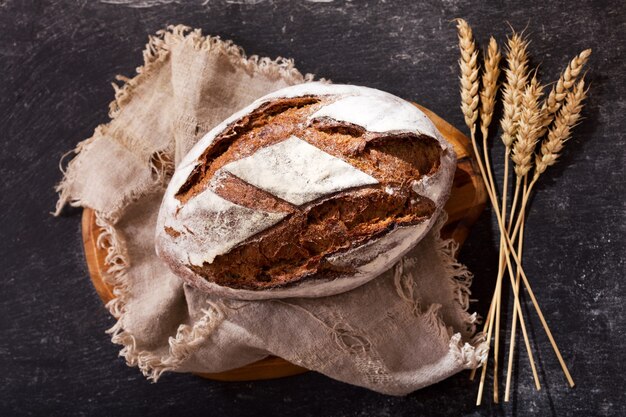 Pane fresco con spighe di grano sul tavolo scuro, vista dall'alto