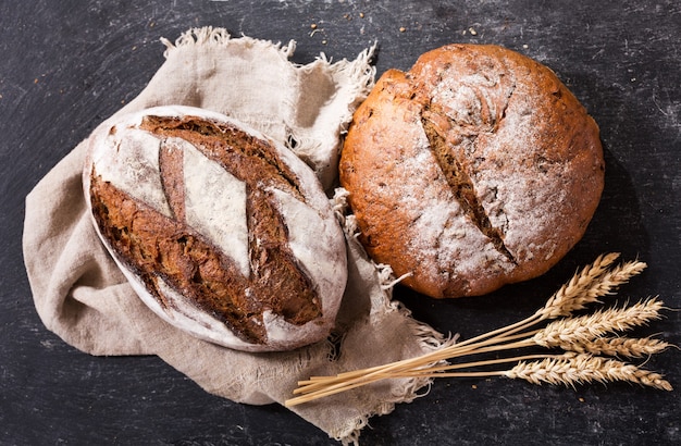 Pane fresco con spighe di grano sul tavolo scuro, vista dall'alto