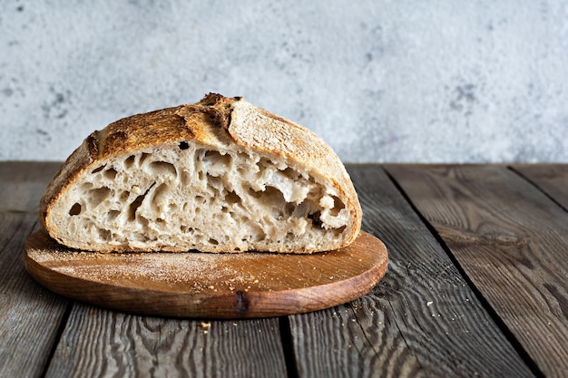 Pane fresco croccante fatto in casa con farina di grano intero a lievitazione naturale non lievitata su fondo di legno