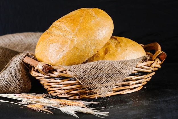 Pane fresco dolce e grano su fondo di legno nero