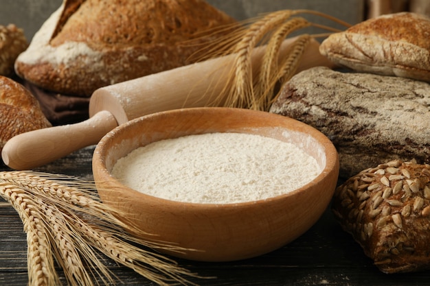 Pane fresco, farina, spighette e mattarello su fondo in legno