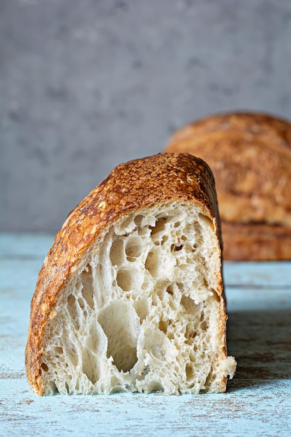Pane fresco fatto in casa a lievitazione naturale con farina integrale su fondo grigio-blu. Cibo salutare.