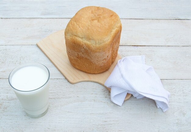 Pane fresco fatto in casa e un bicchiere di yogurt biologico naturale fatto in casa su uno sfondo di legno bianco