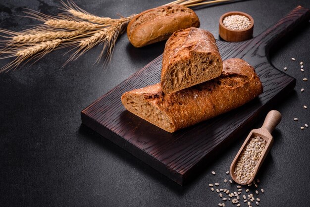 Pane fresco su sfondo nero, vista dall'alto, copia spazio. Varie pagnotte di grano e pane di segale fatte in casa appena sfornate