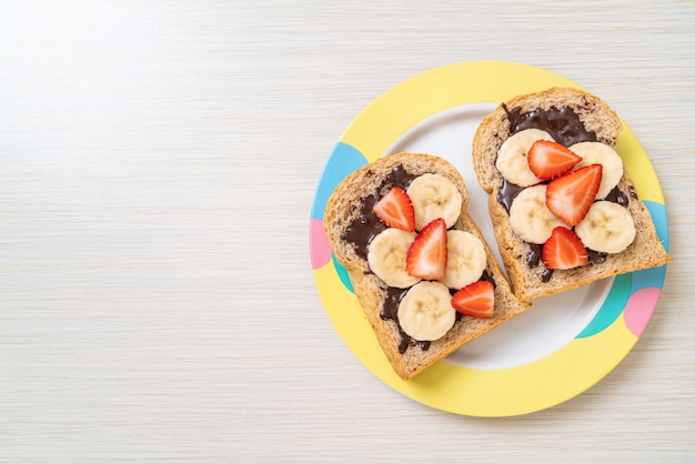 pane integrale con banana fresca, fragole e cioccolato