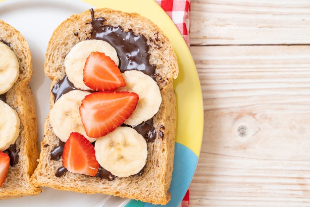 pane integrale con banana fresca, fragole e cioccolato