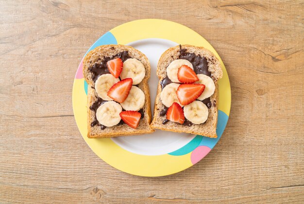 pane integrale con banana fresca, fragole e cioccolato